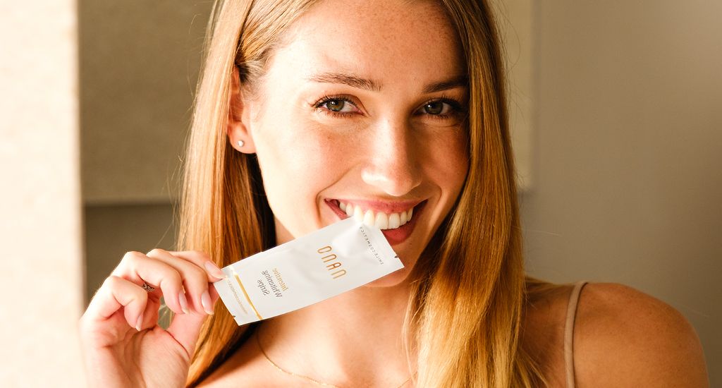 Smiling woman holding a Nano whitening strips sachet